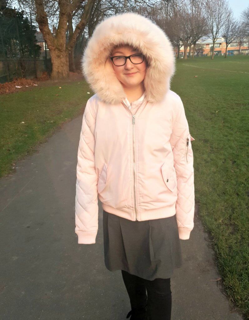 easy bedtime routine for kids post picture of girl in a pink coat with fur hood standing in a park