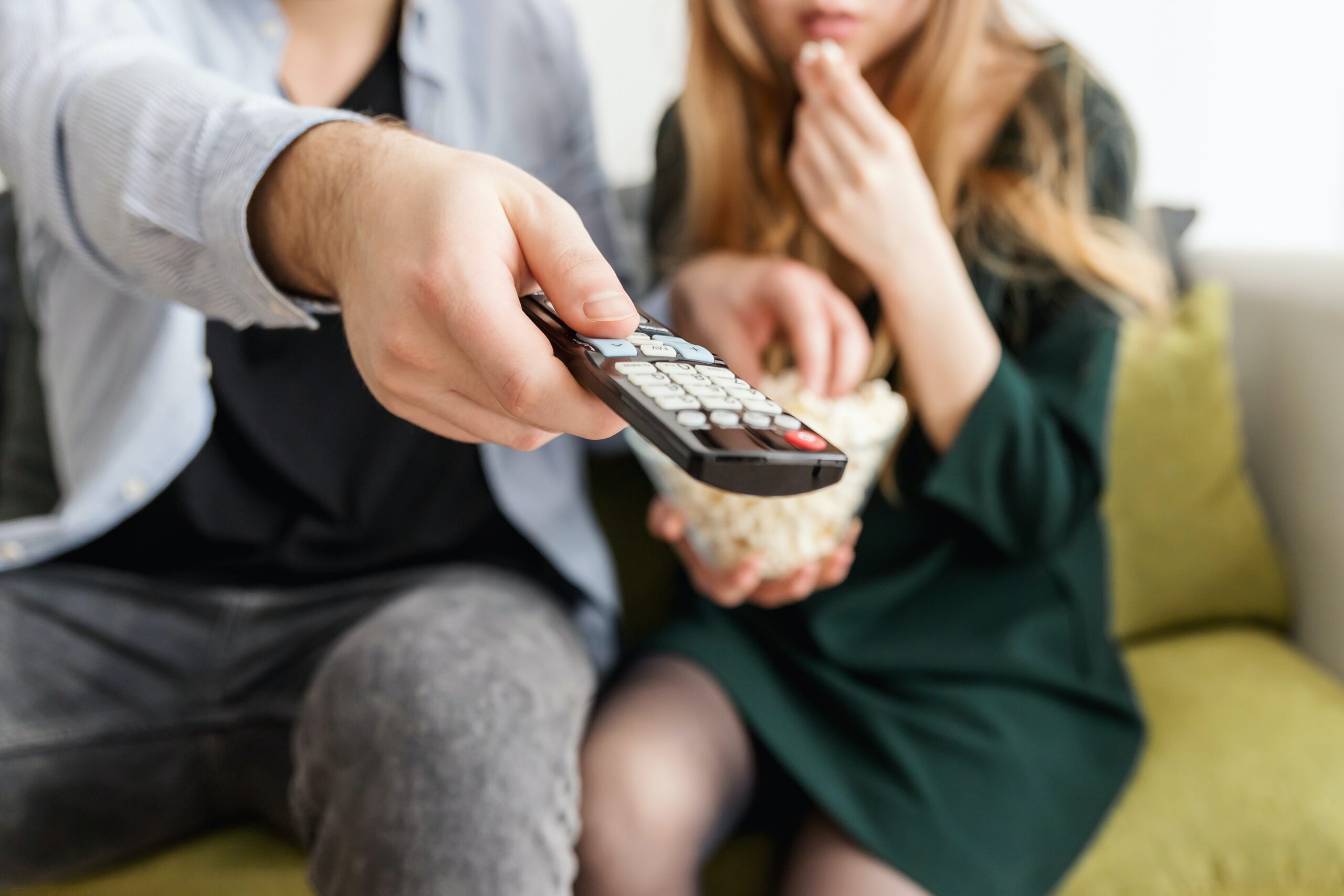 close up of a man and woman's knees holding a tv remote