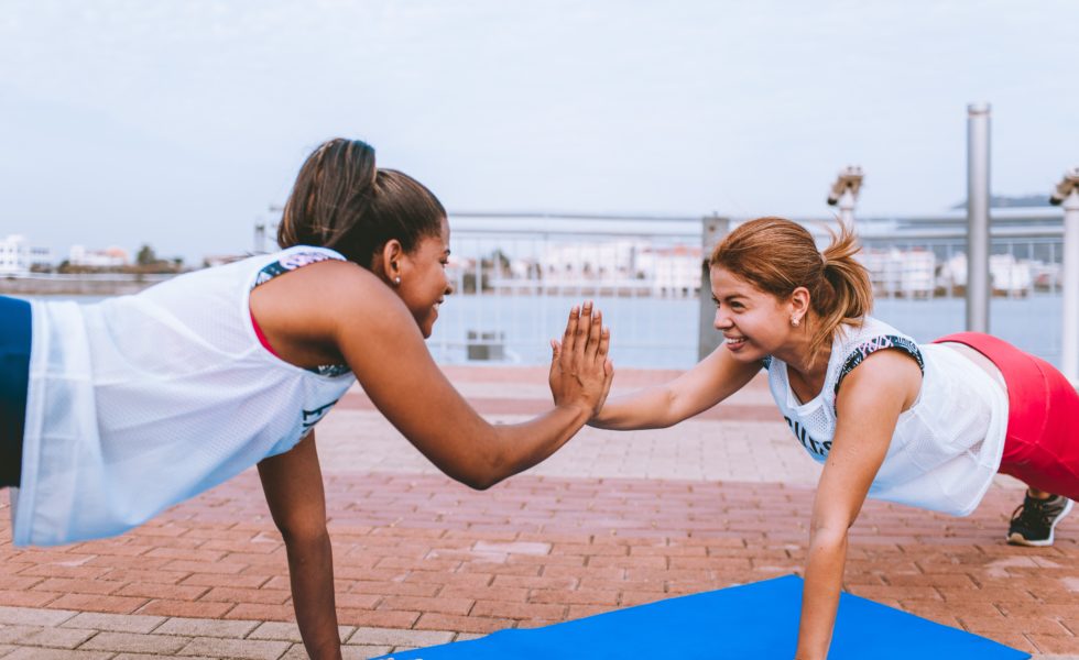 two women in plank positions high fiving each other