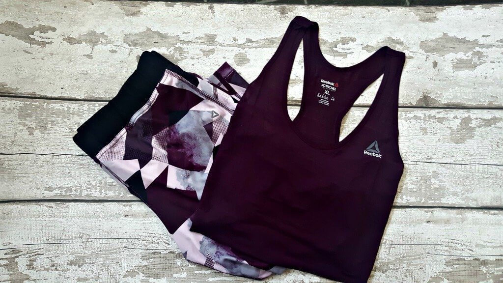 flatlay of a plus size active wear outfit in deep purple on a background for return to fitness post