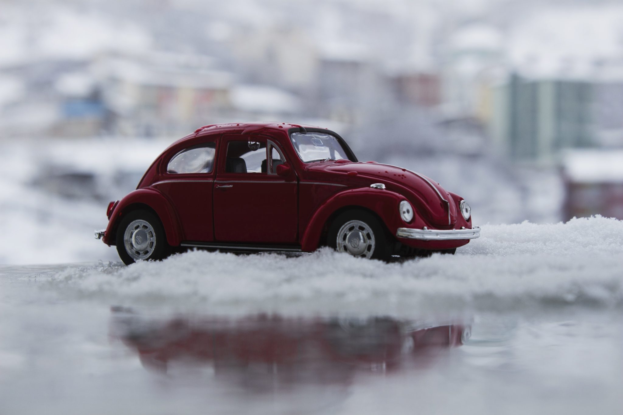 a small red beetle car in snow