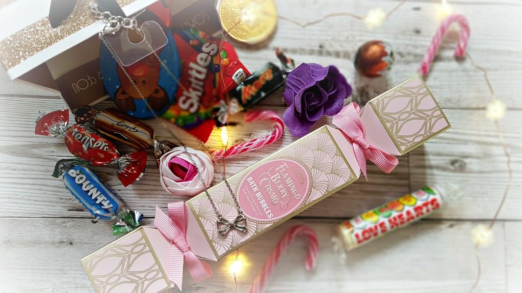gift bag with sweets, bath products and a silver bow necklace surrounded by led lights on copper wire