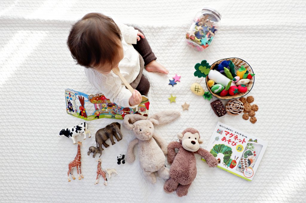 child on a white blanket surrounded by toys