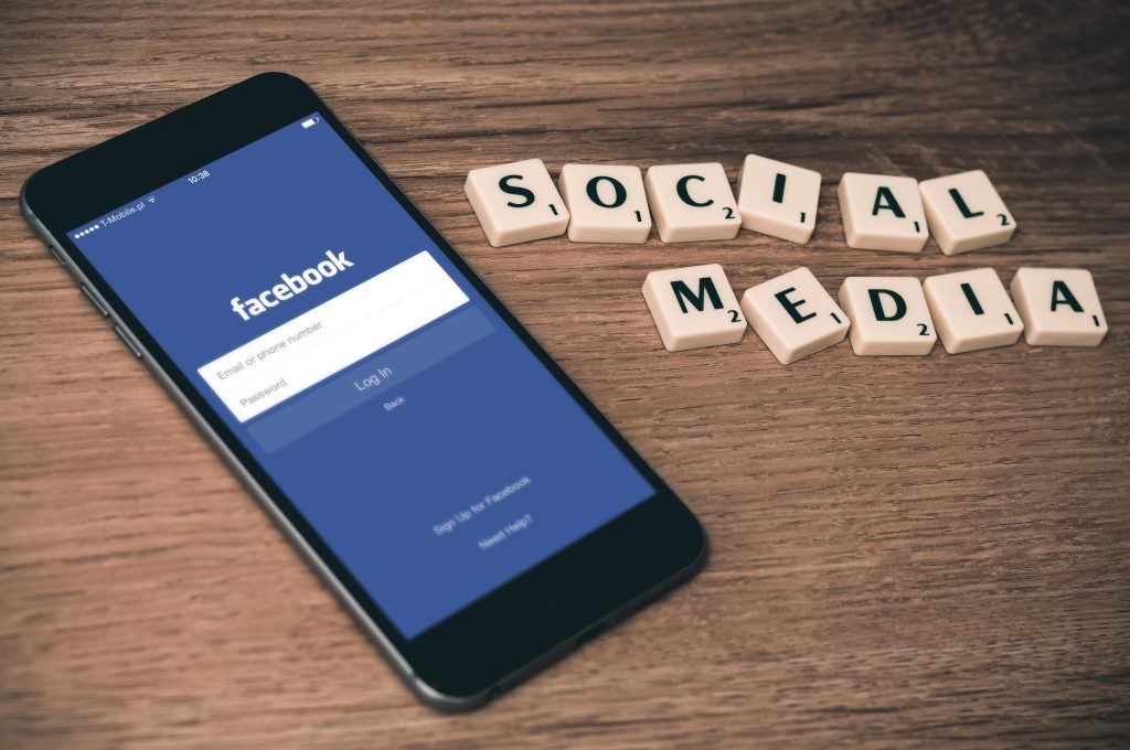 a mobile phone with facebook on the screen and scrable letters spelling social media