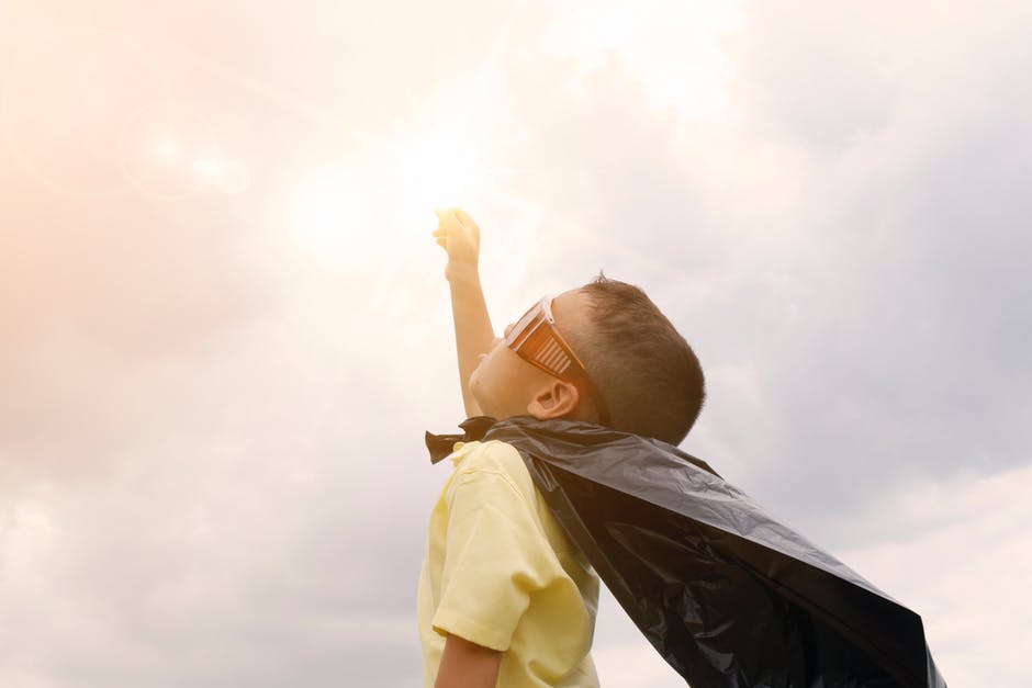 kid in a superhero cape with fist punched in the air