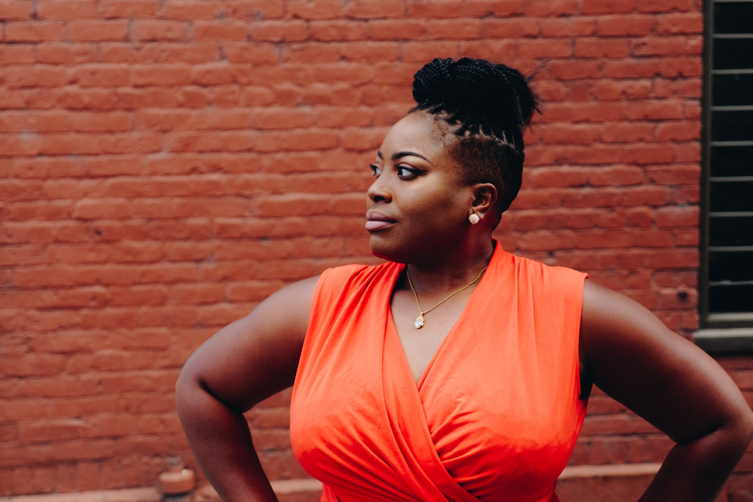 womans standing with hands on hips and an orange v neck top on