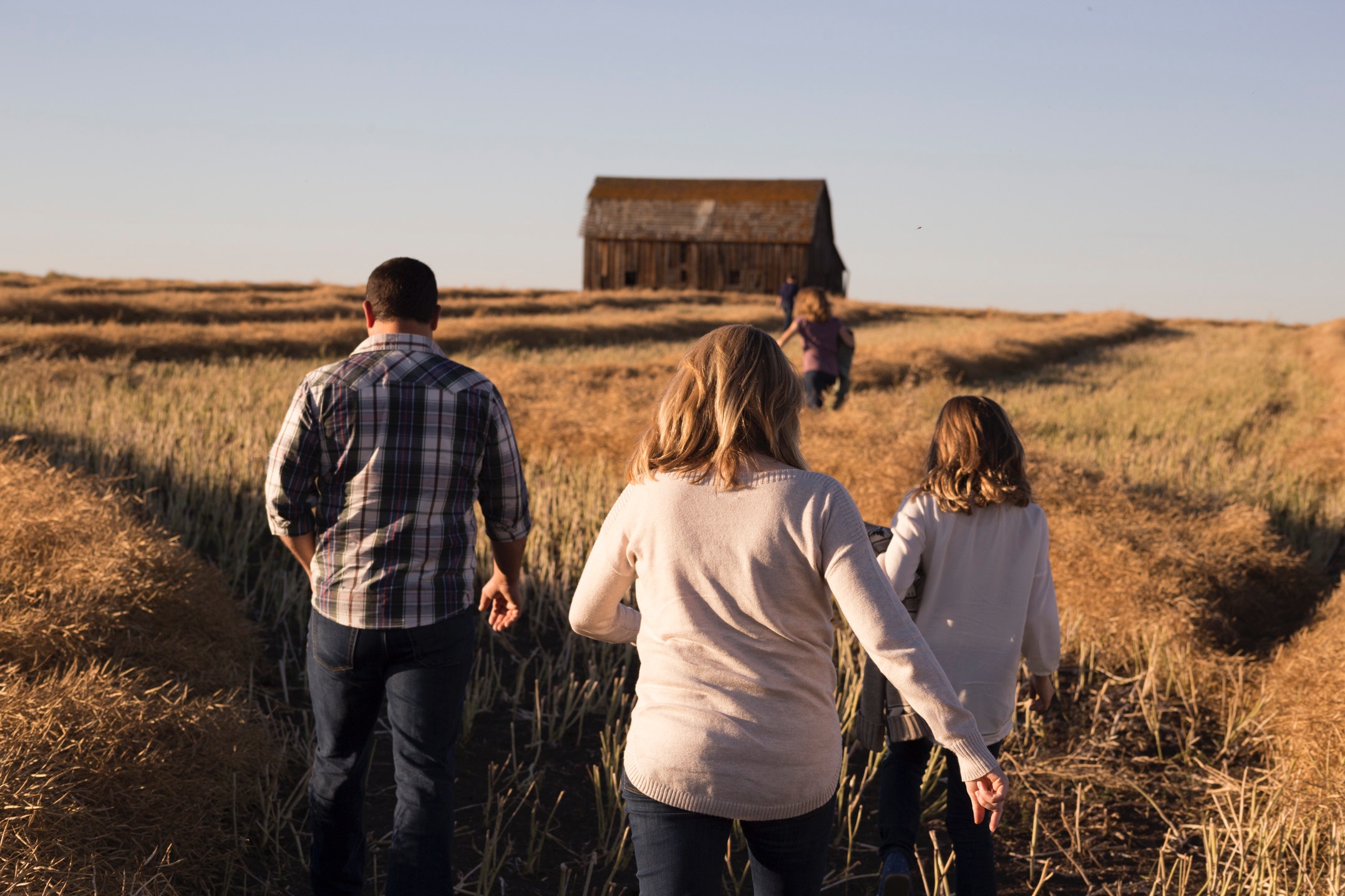 family walking towards a barn across a field