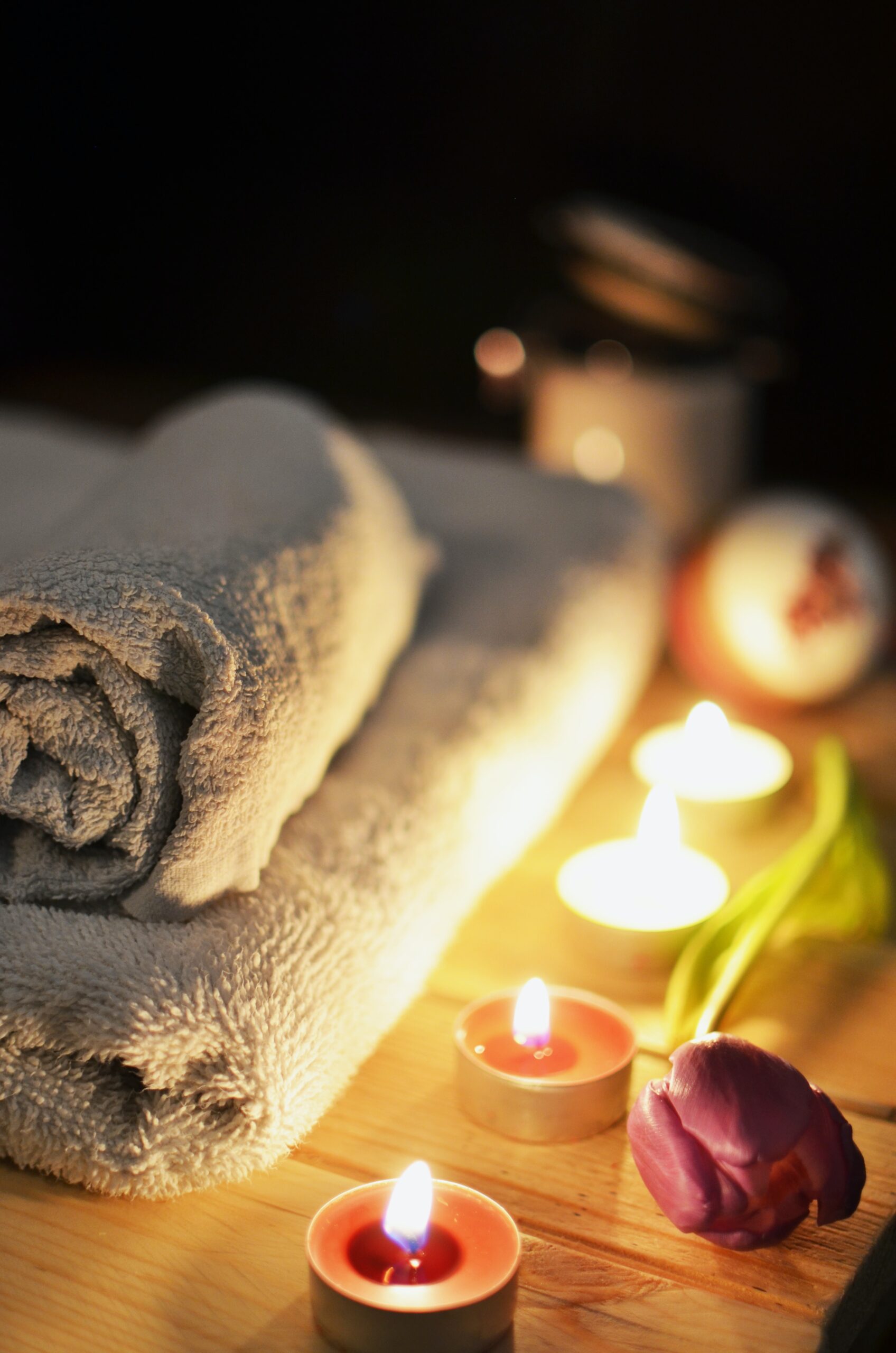 low light image of folded towels and lit tealights