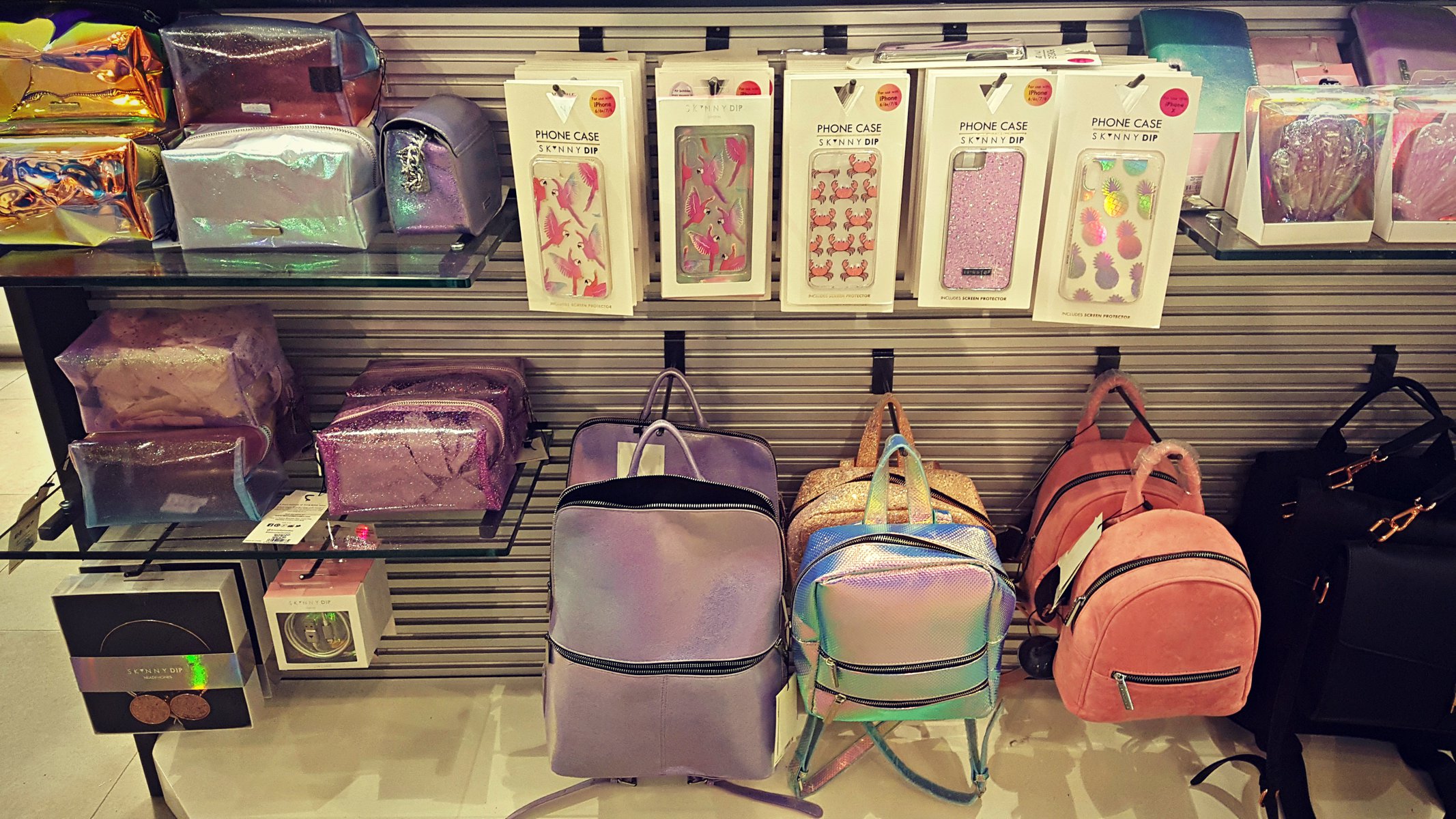 a range of skinny dip make up bags, phone cases and backpacks at a till point in an outfit store