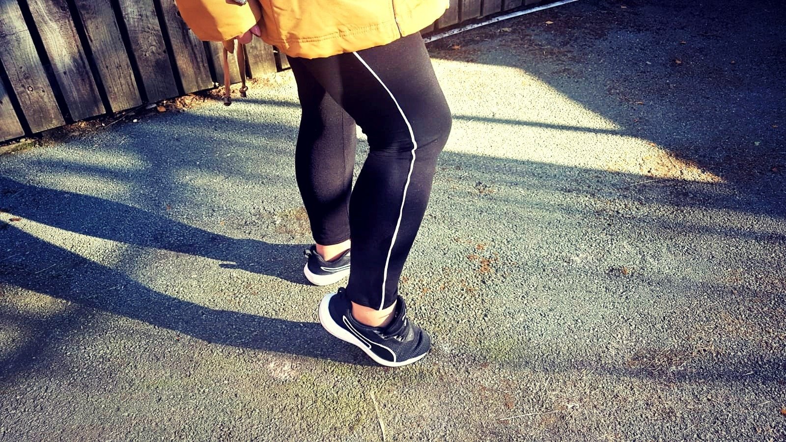 black leggings with white piping under a coat with black and white trainers
