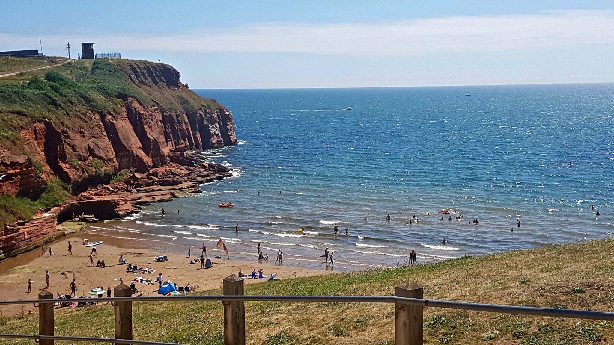 a busy beach surrounded by cliffs