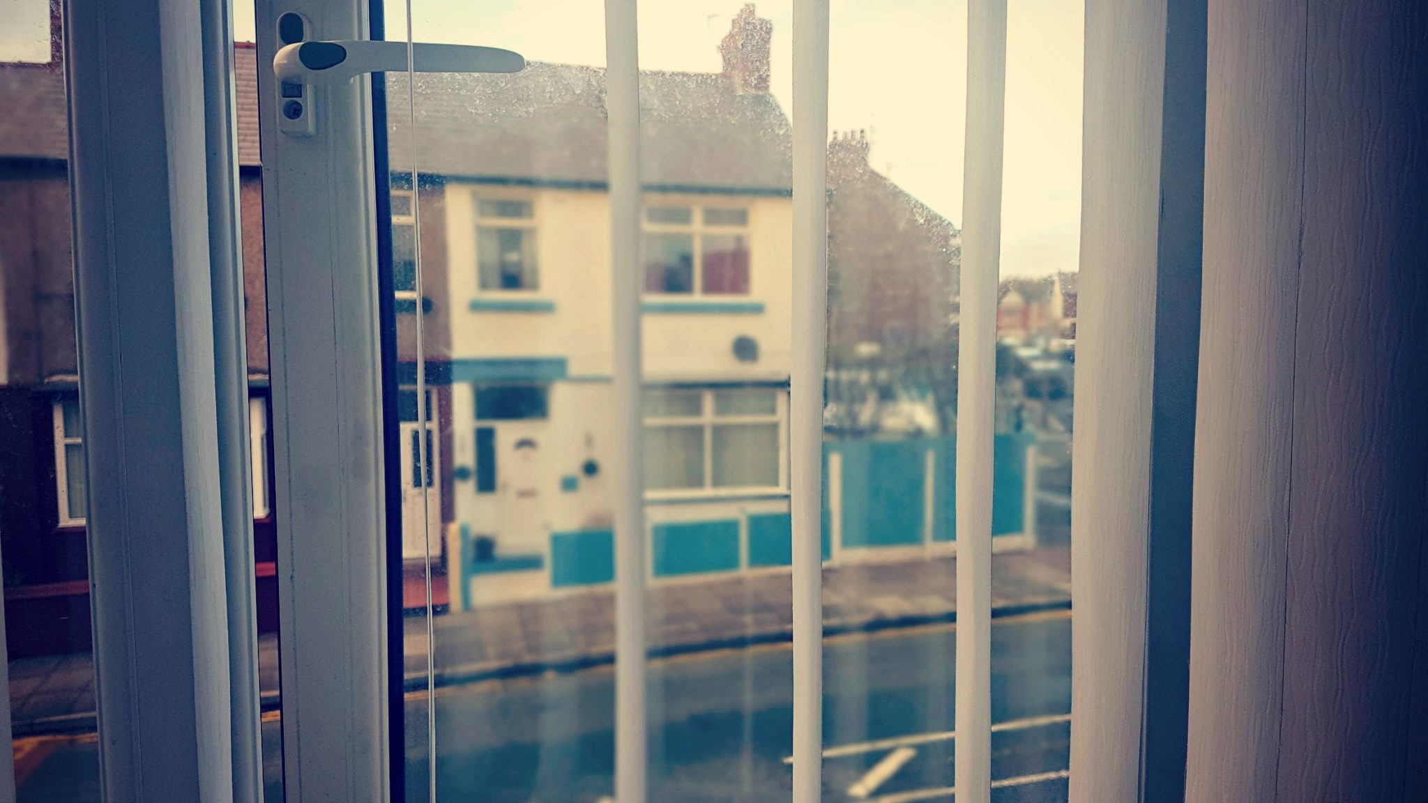 a view through an open double glazed window with blind slats open