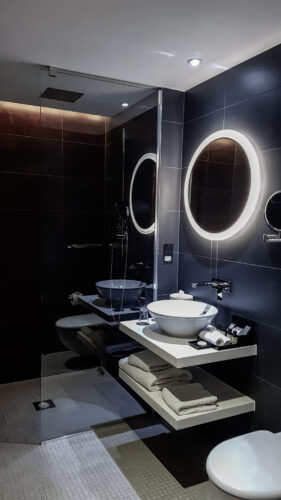 a fully tiled bathroom with sink, toilet and walk in shower in view in the pullman hotel liverpool 
