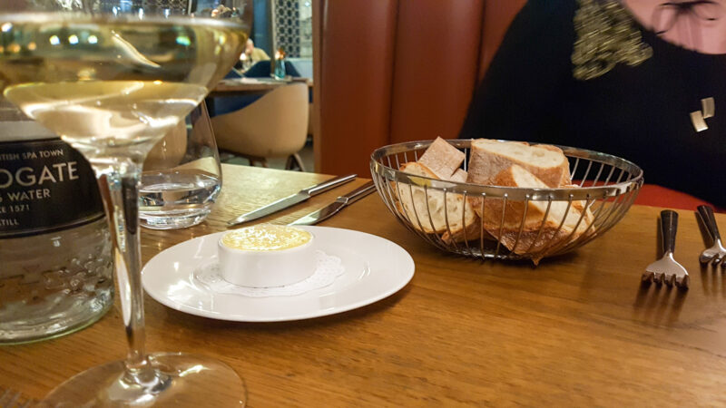 selective focus shot of a wire basket with sourdough in and the side of a bottle of wine at the edge of the image