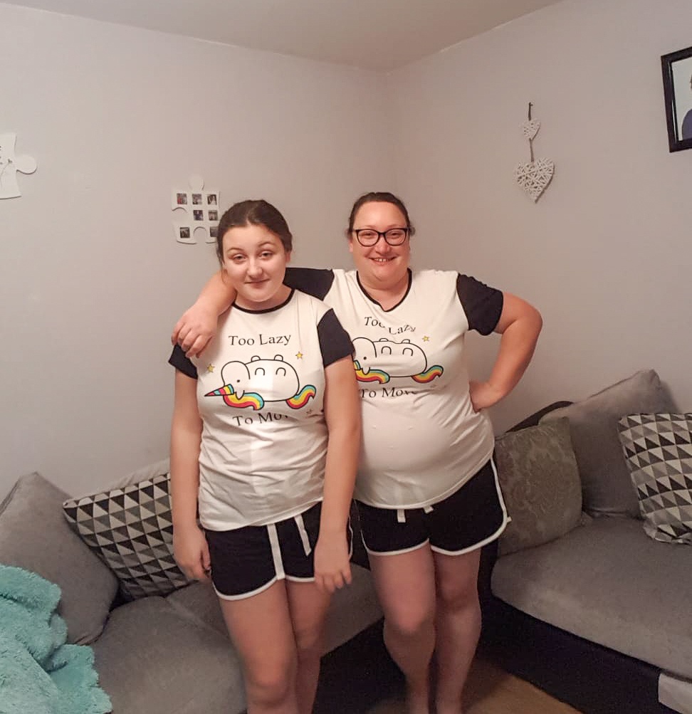 two women wearing matching unicorn pjs from pyjama factory in a living room setting