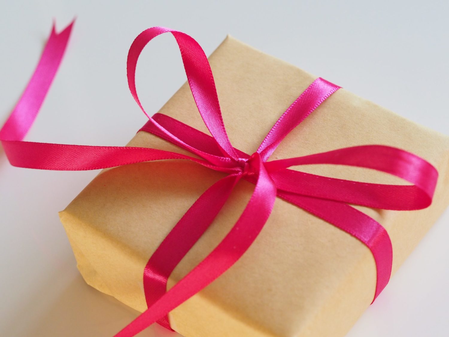 a gift wrapped in brown paper with a pink ribbon tied in a bow