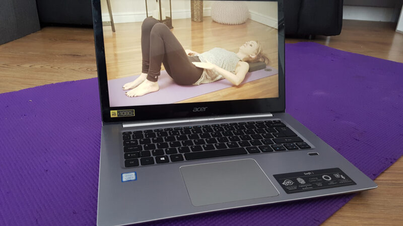 a laptop on a yoga mat showing a woman in a pilates pose