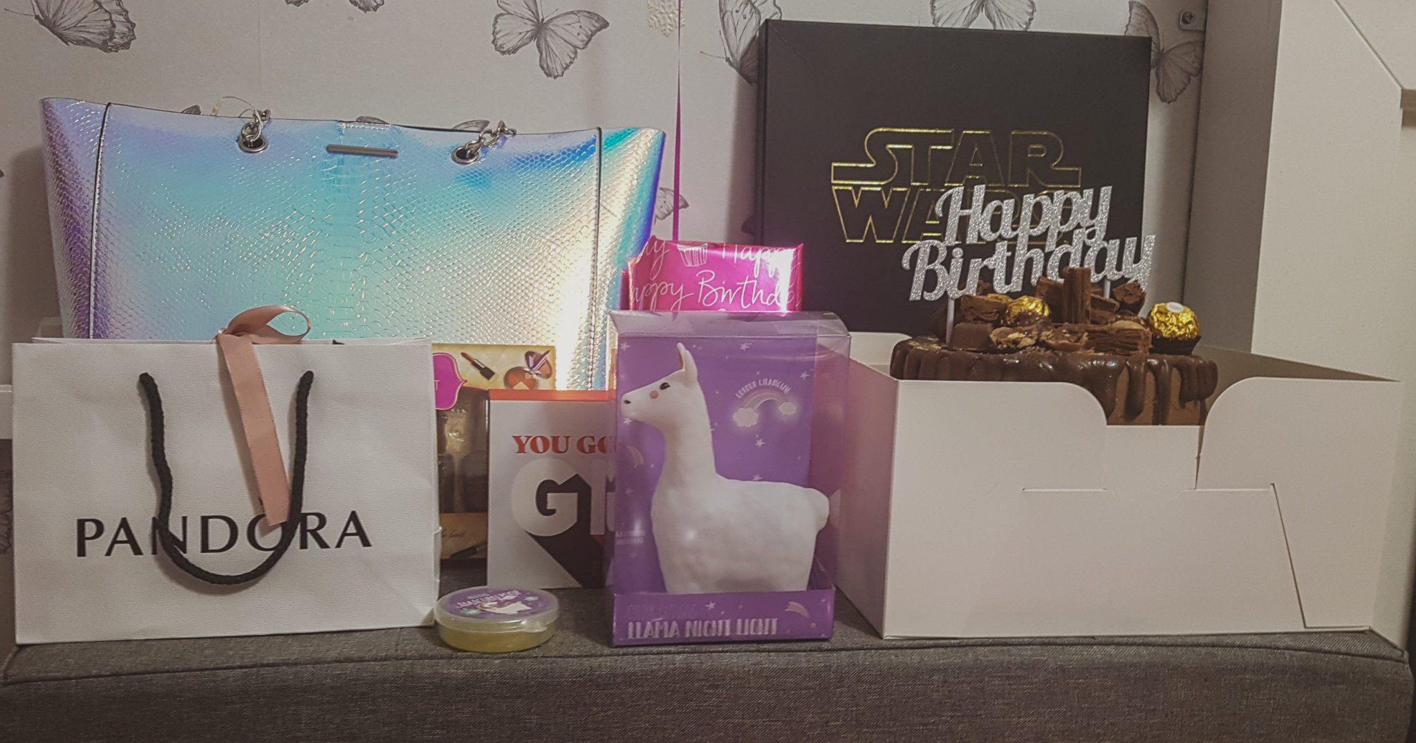 a selection of birthday gifts including a pandora bag, llama light, holographic handbag and chocolate birthday cake in a box
