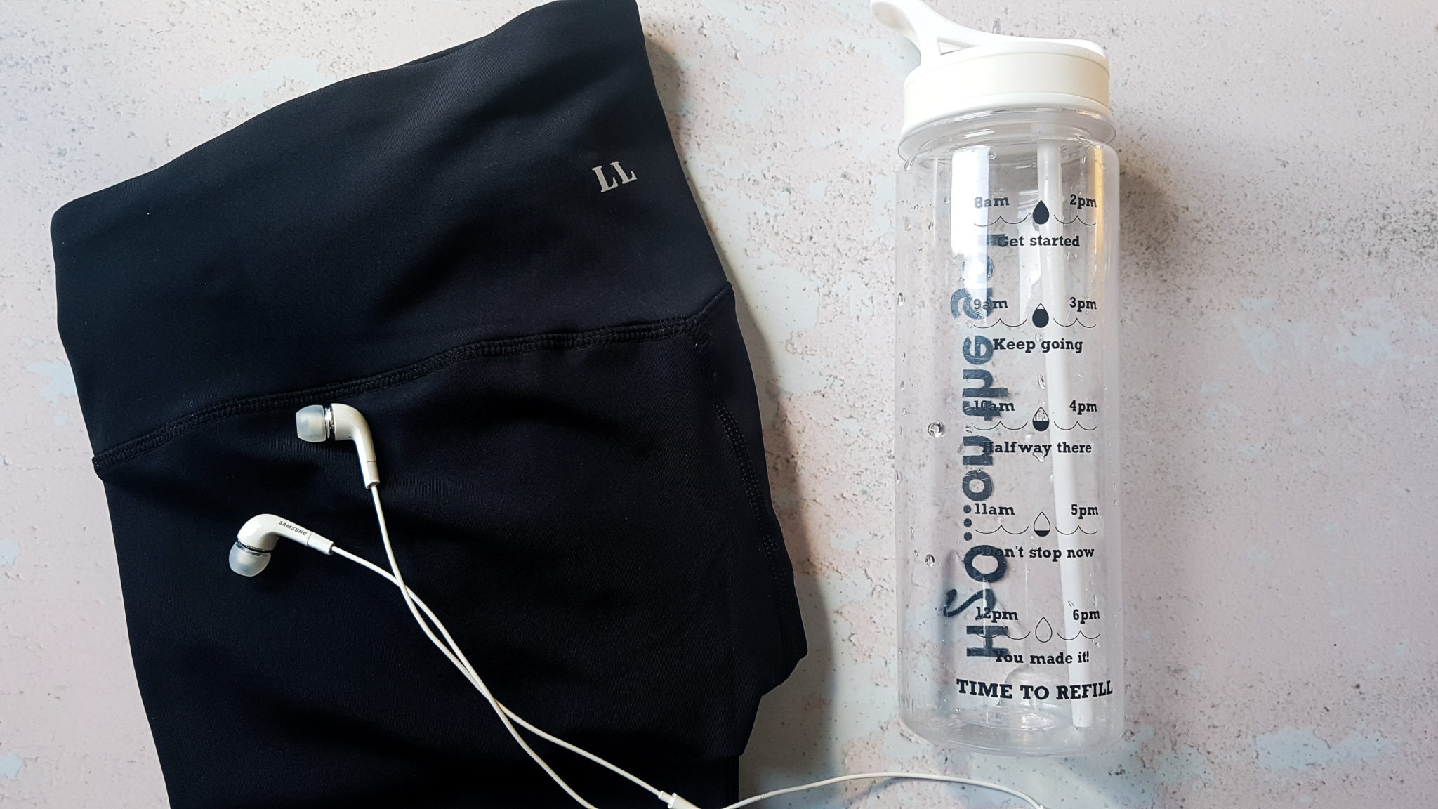 black love leggings sports legging in flatlay with white in ear headphones and a water bottle