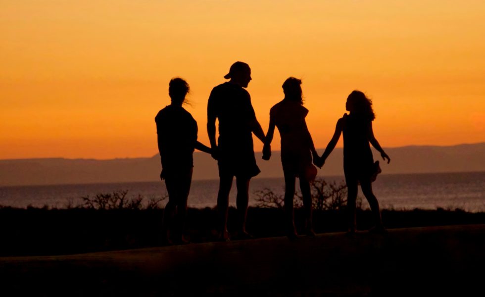a picture of a family silhouette on the beach at sunset