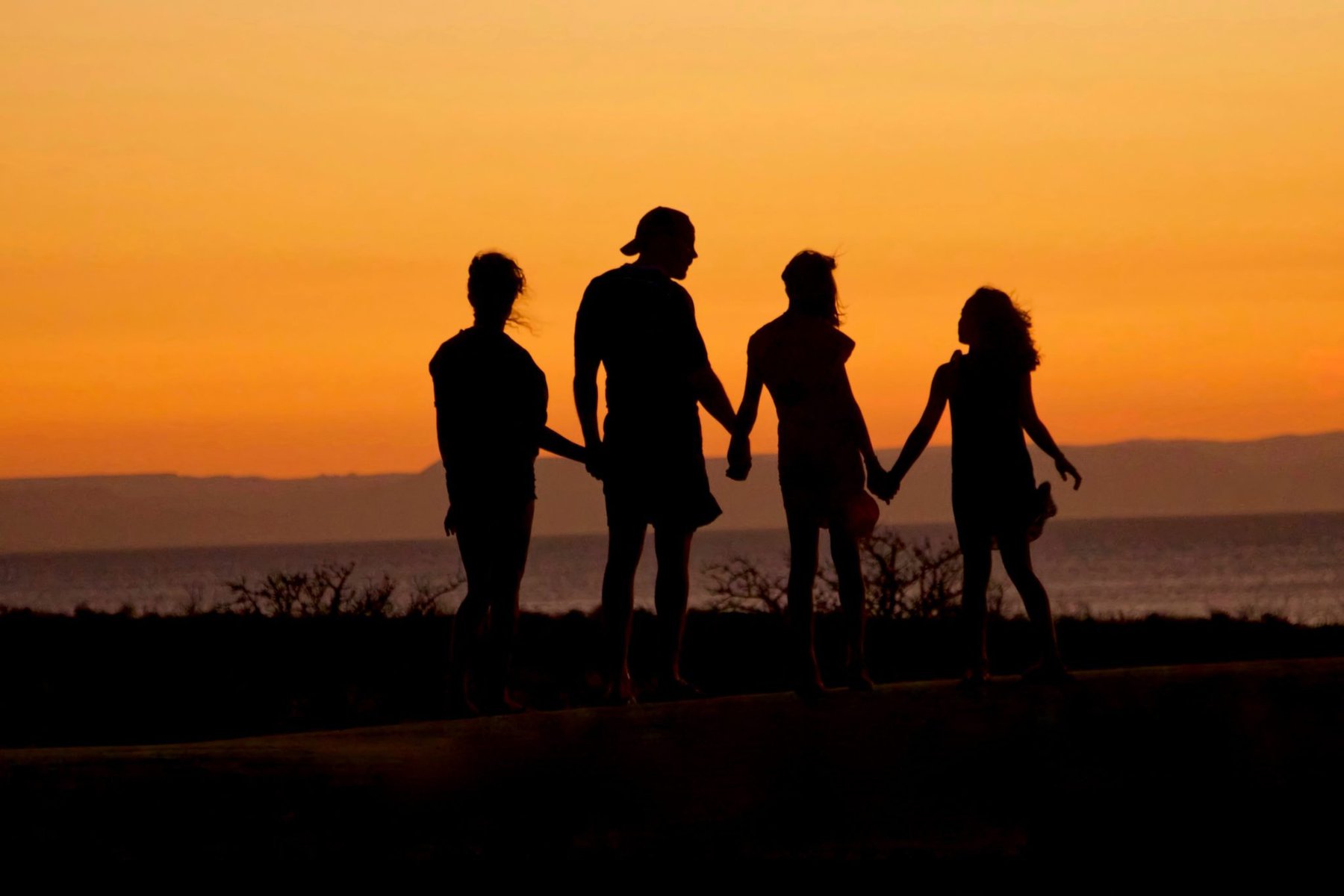 family standing in a silhoutee at sunset