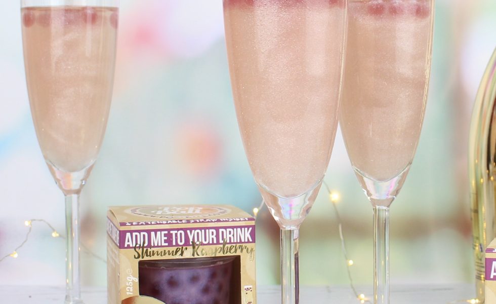image of champagne glasses against a blurred background with a box of popaball