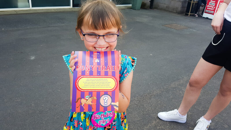 young girl holding a pony race card