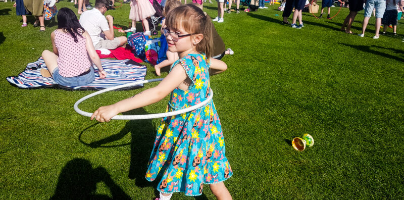 young girl wearing glasses and a dress with a hula hoop
