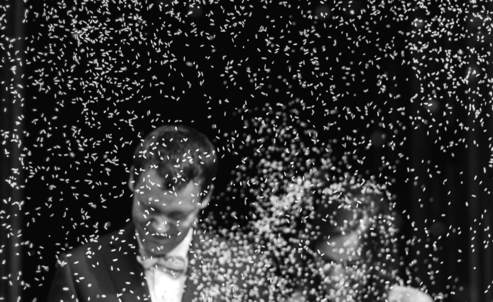 grey scale wedding picture of bride and groom walking through confetti
