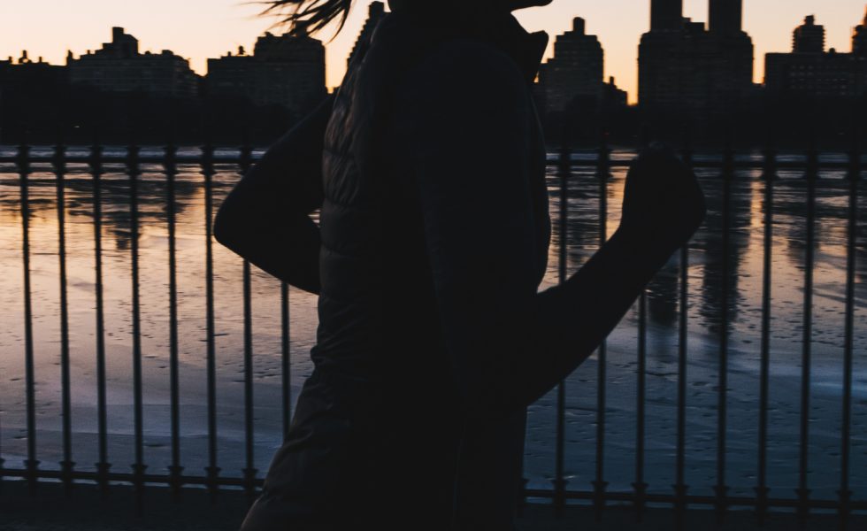 silhouette of woman running in front of a lake