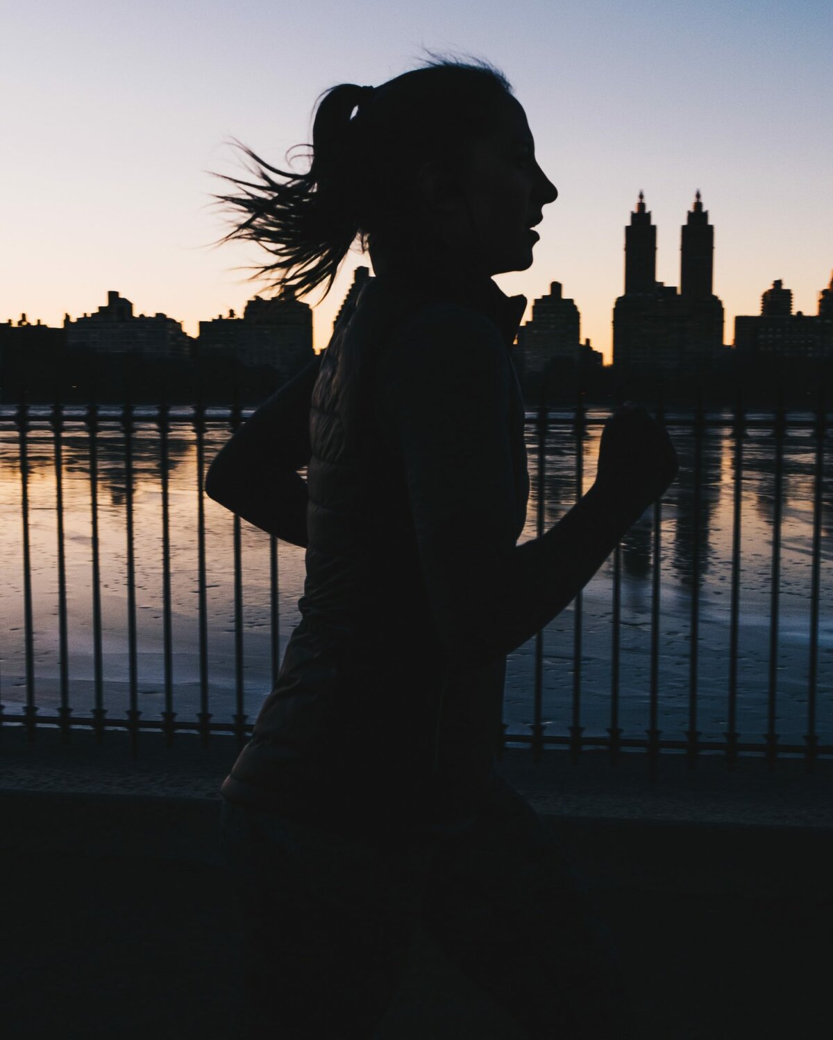 silhouette of woman running in front of a lake