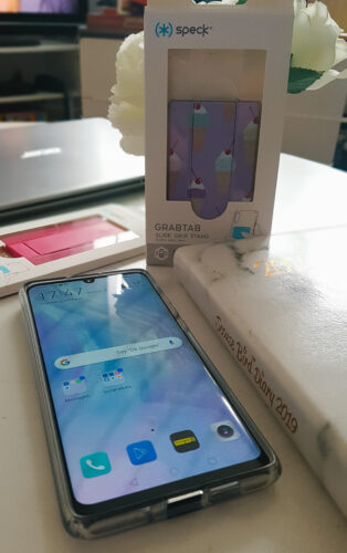 a p30 pro phone on a table surround by a phone case and grab tab from speck