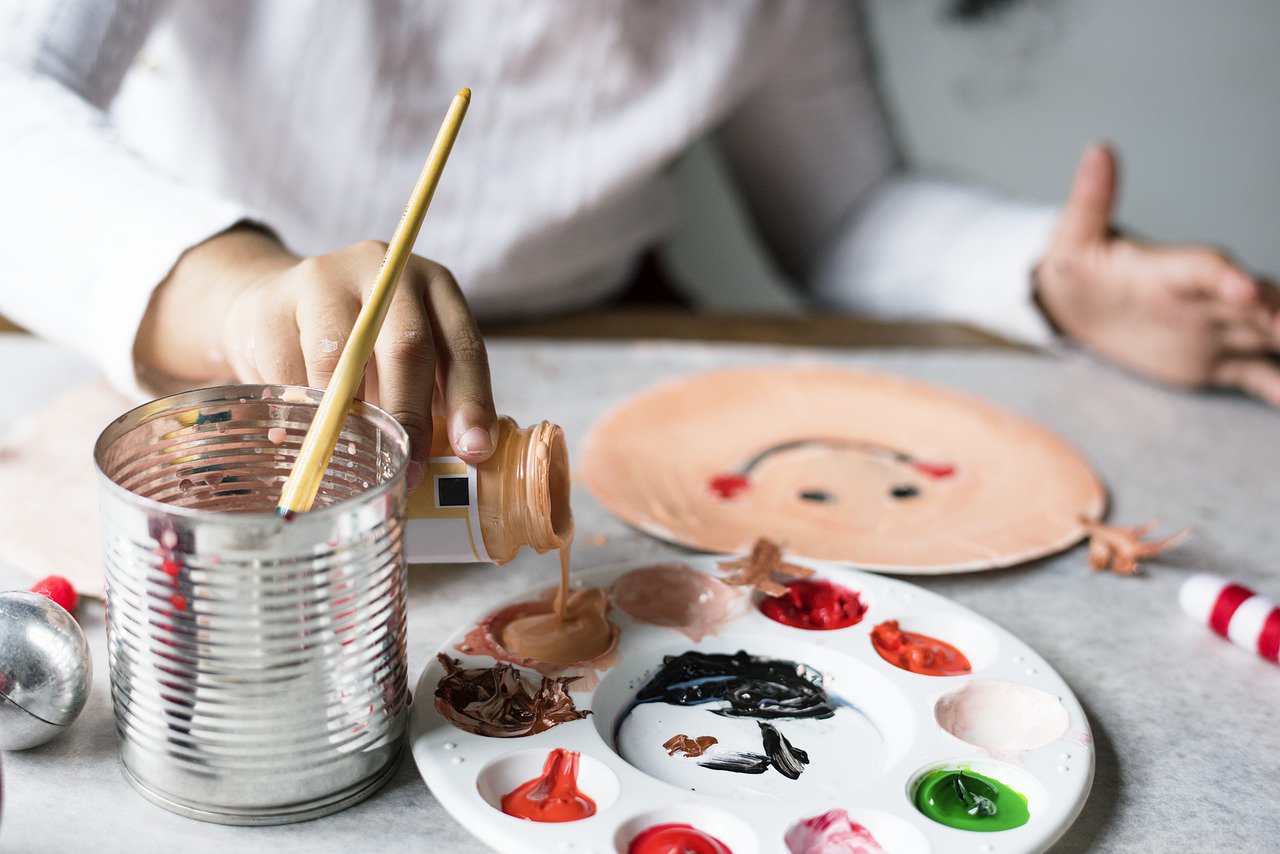 a child painting with painting items on a desk in front of them