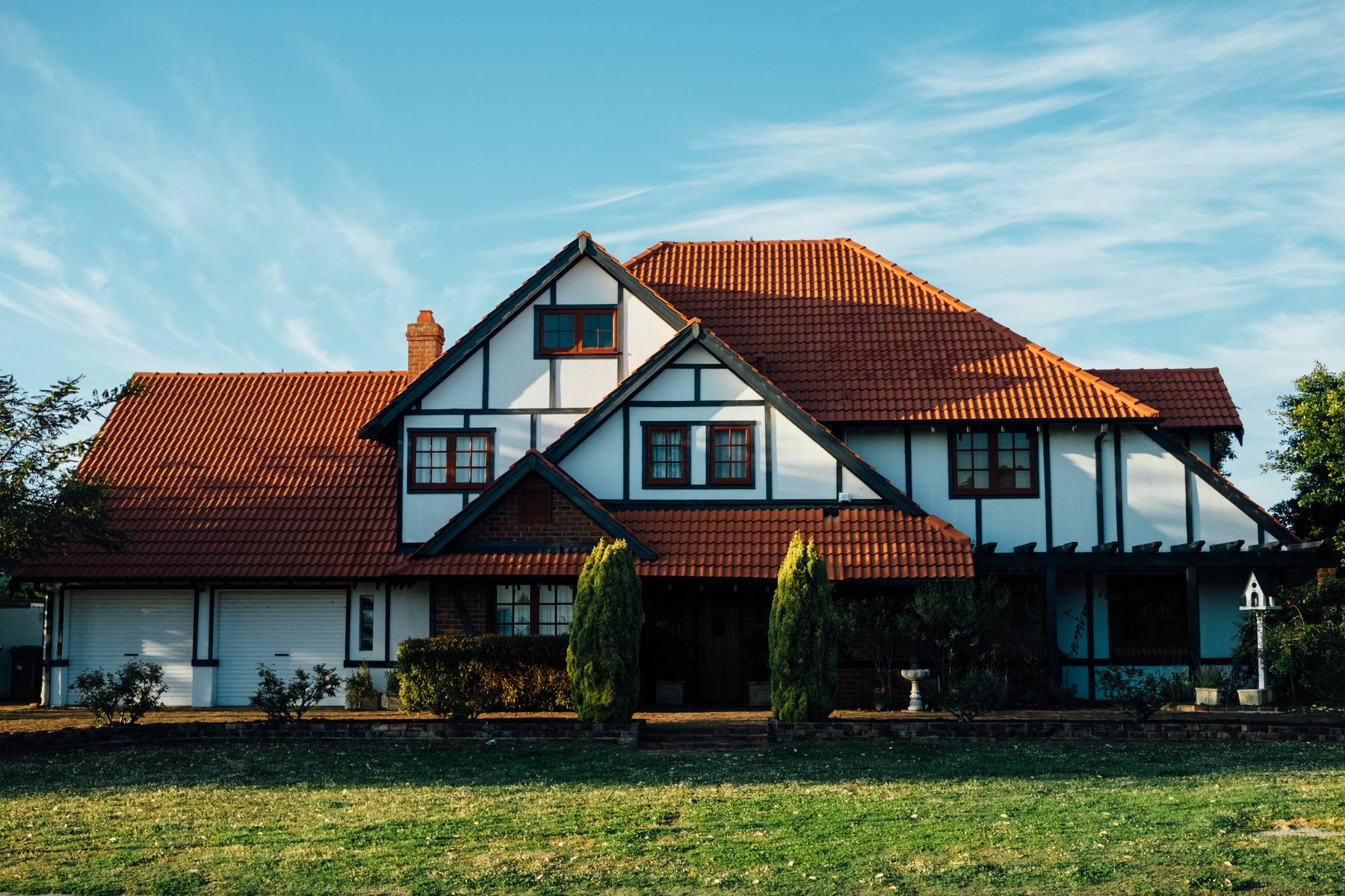 double storey house with white front and a manicured lawn out front