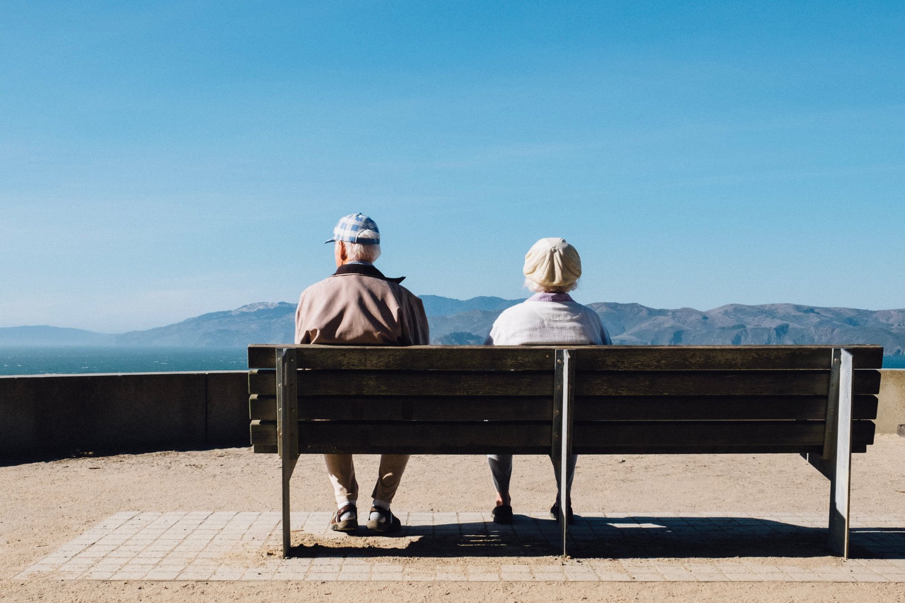couple sat on a bench looking out to a mountain in the distance