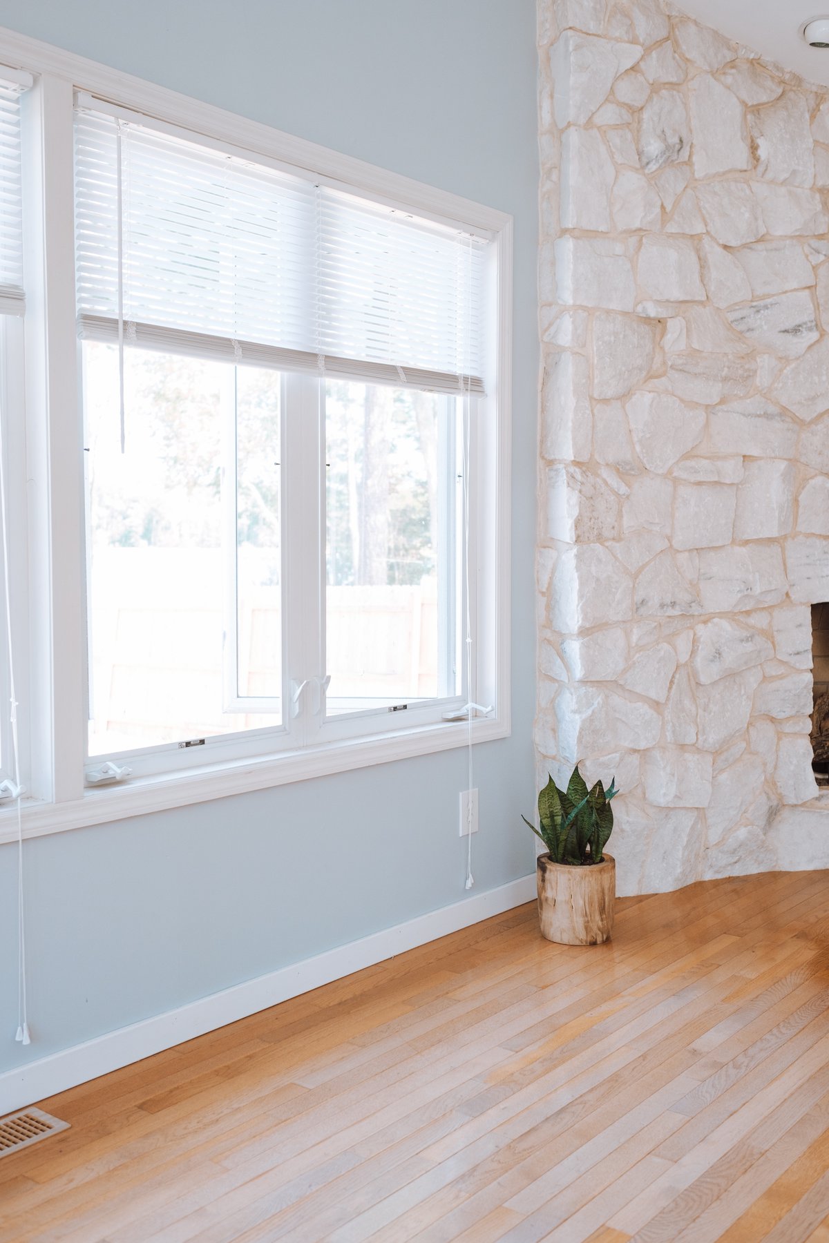 a white wall with window and laminate flooring