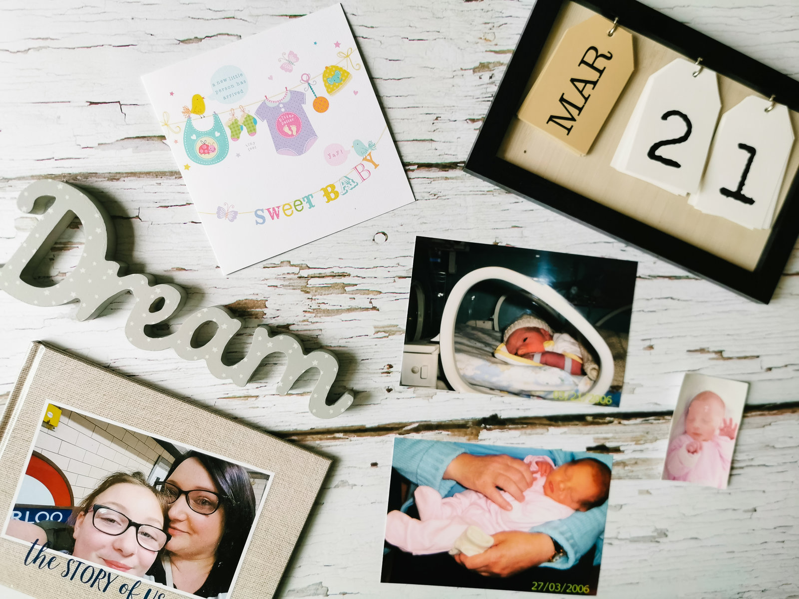 a flatlay image of baby pictures and a card and plaque spelling out dream