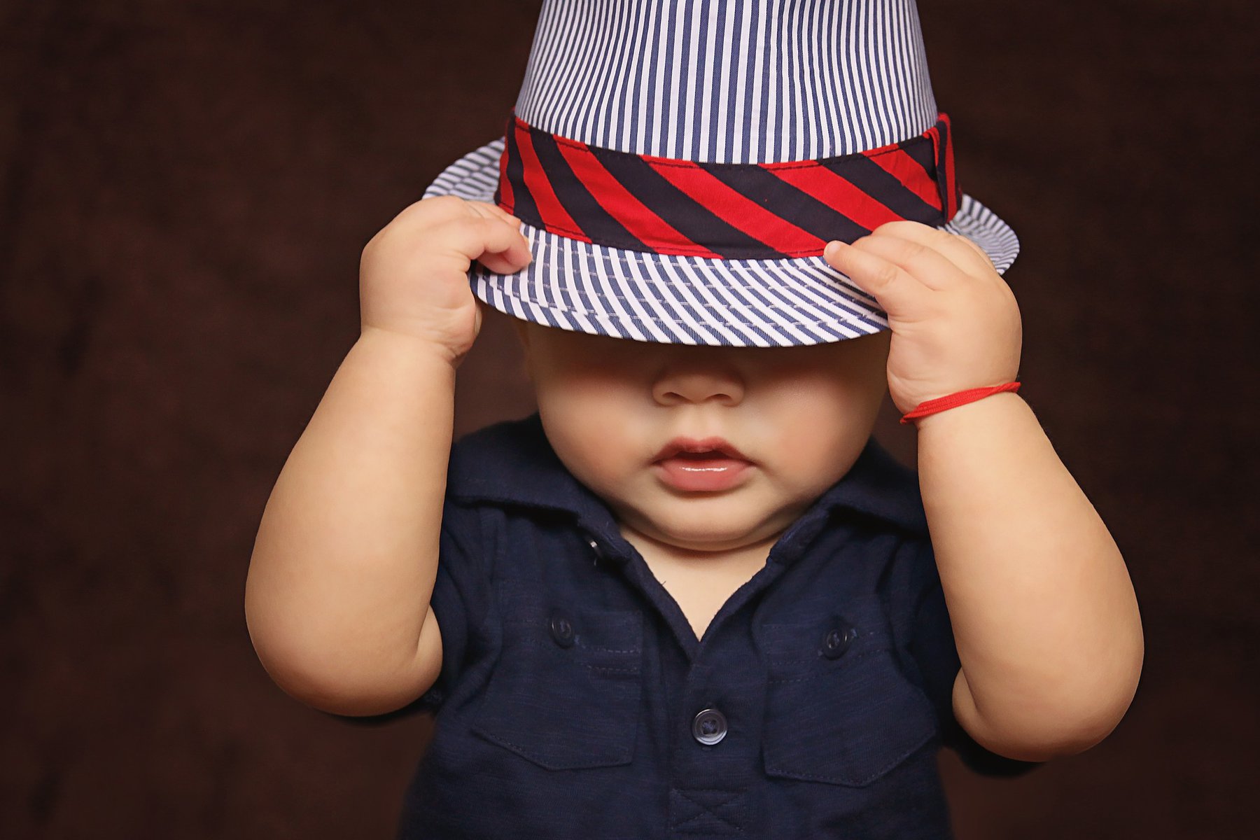toddler wearing a striped hat pulled over face
