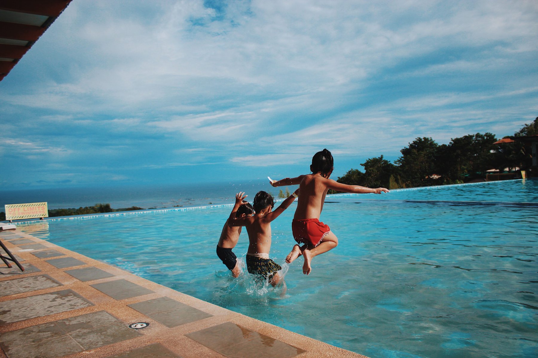 2 kids jumping into a pool