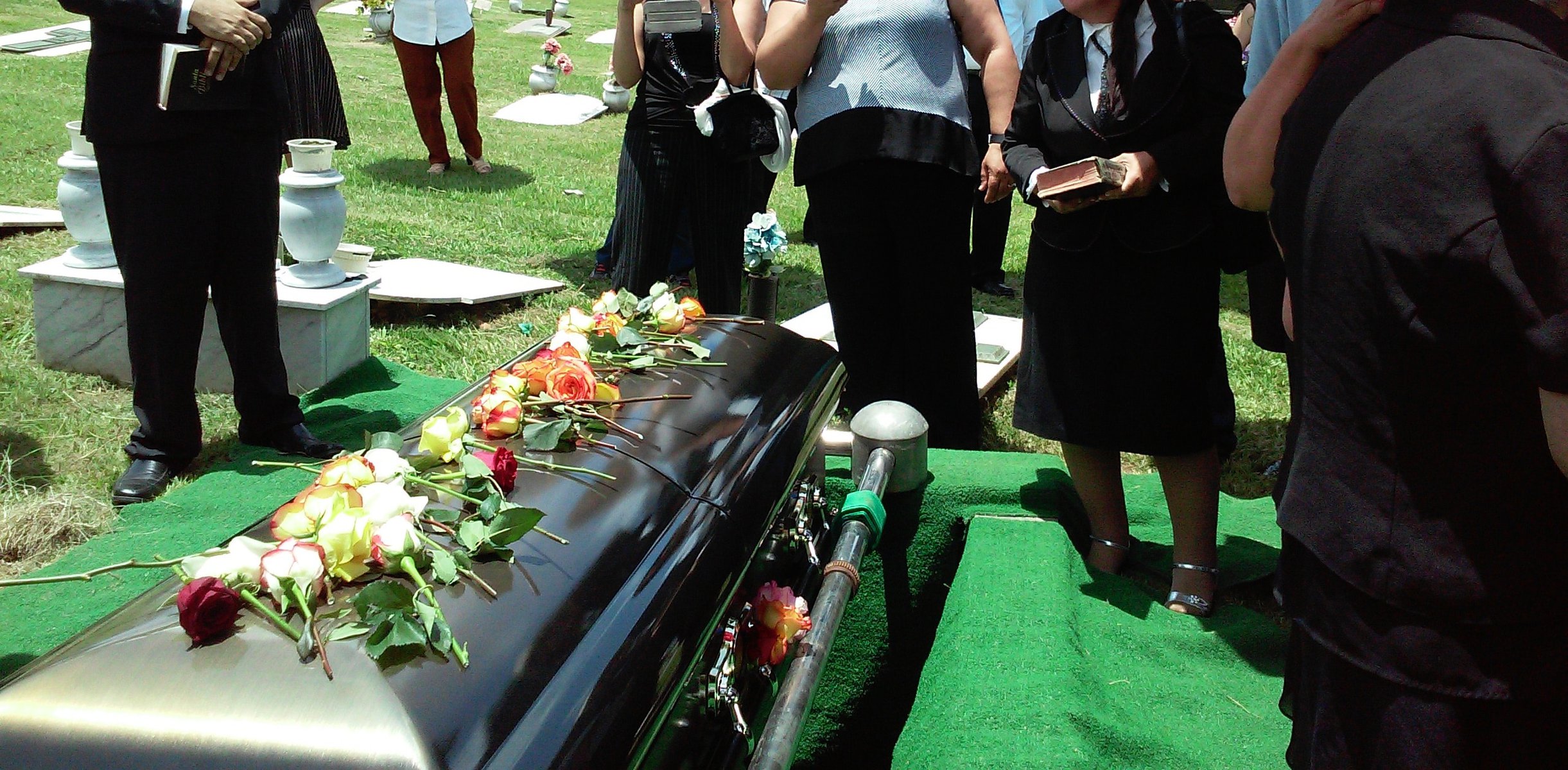 people sstanding around a casket at a funeral