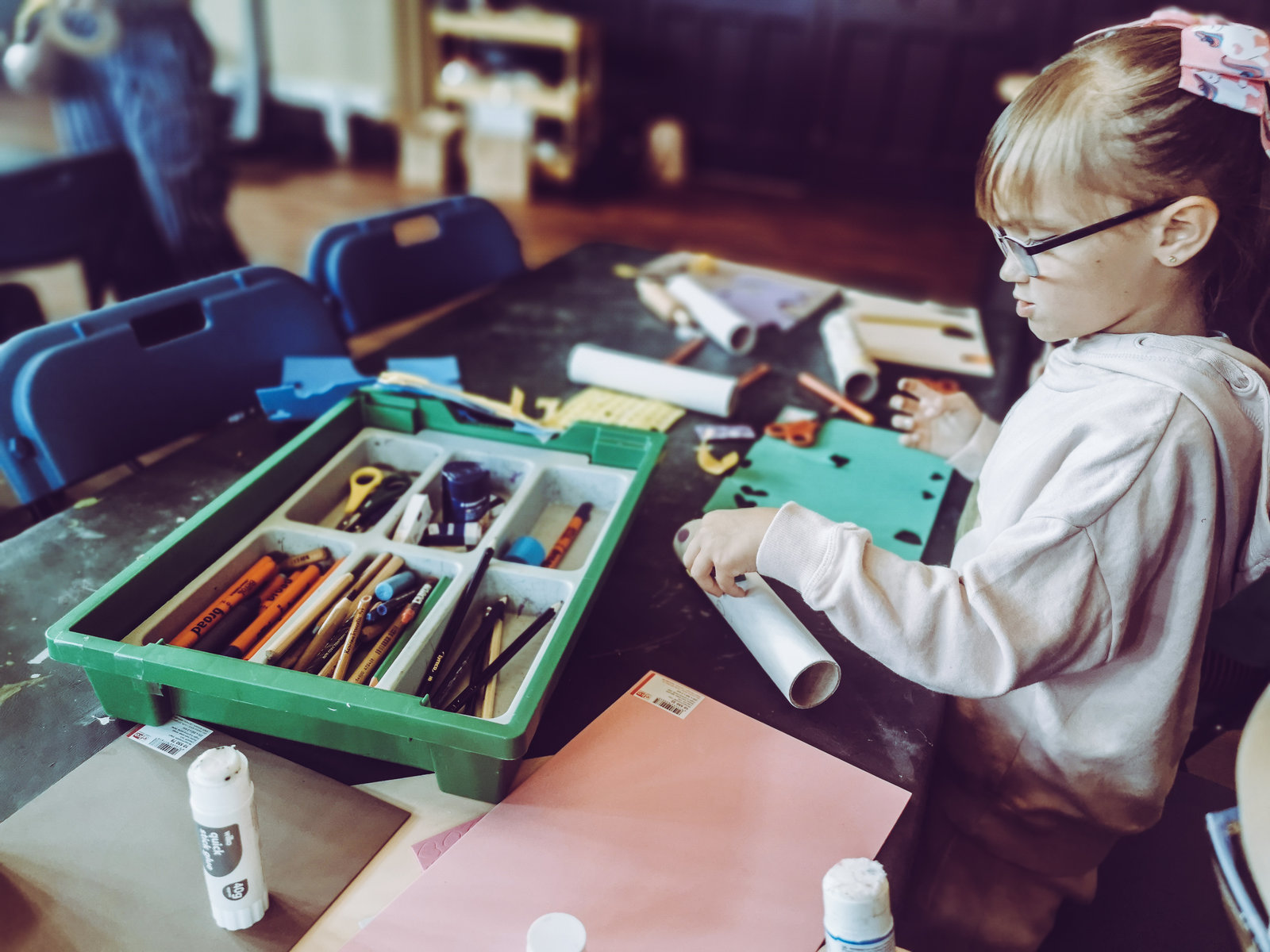 young girl at a table surrounded by craft supplies