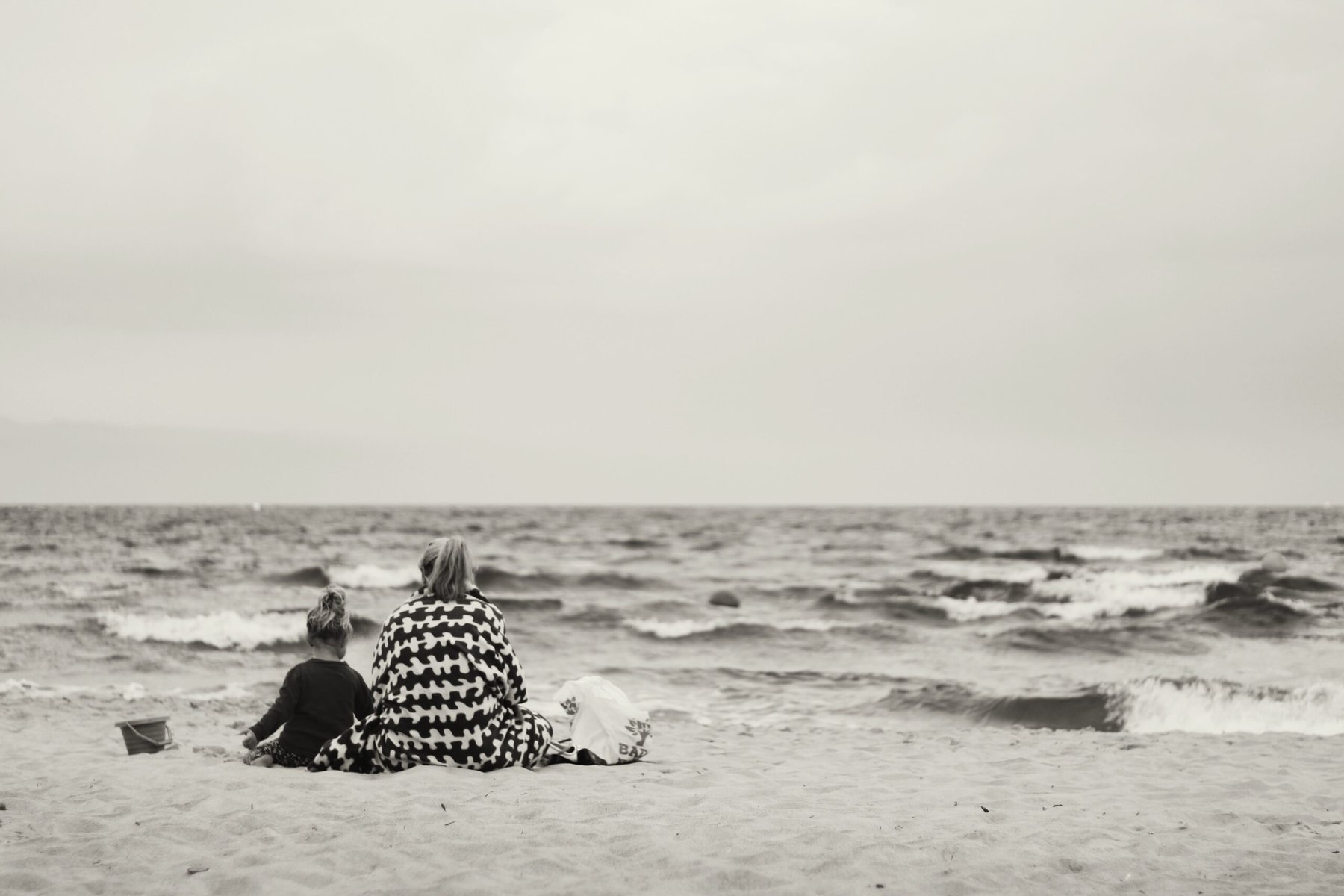 black and white image of mother and child sat on a beach