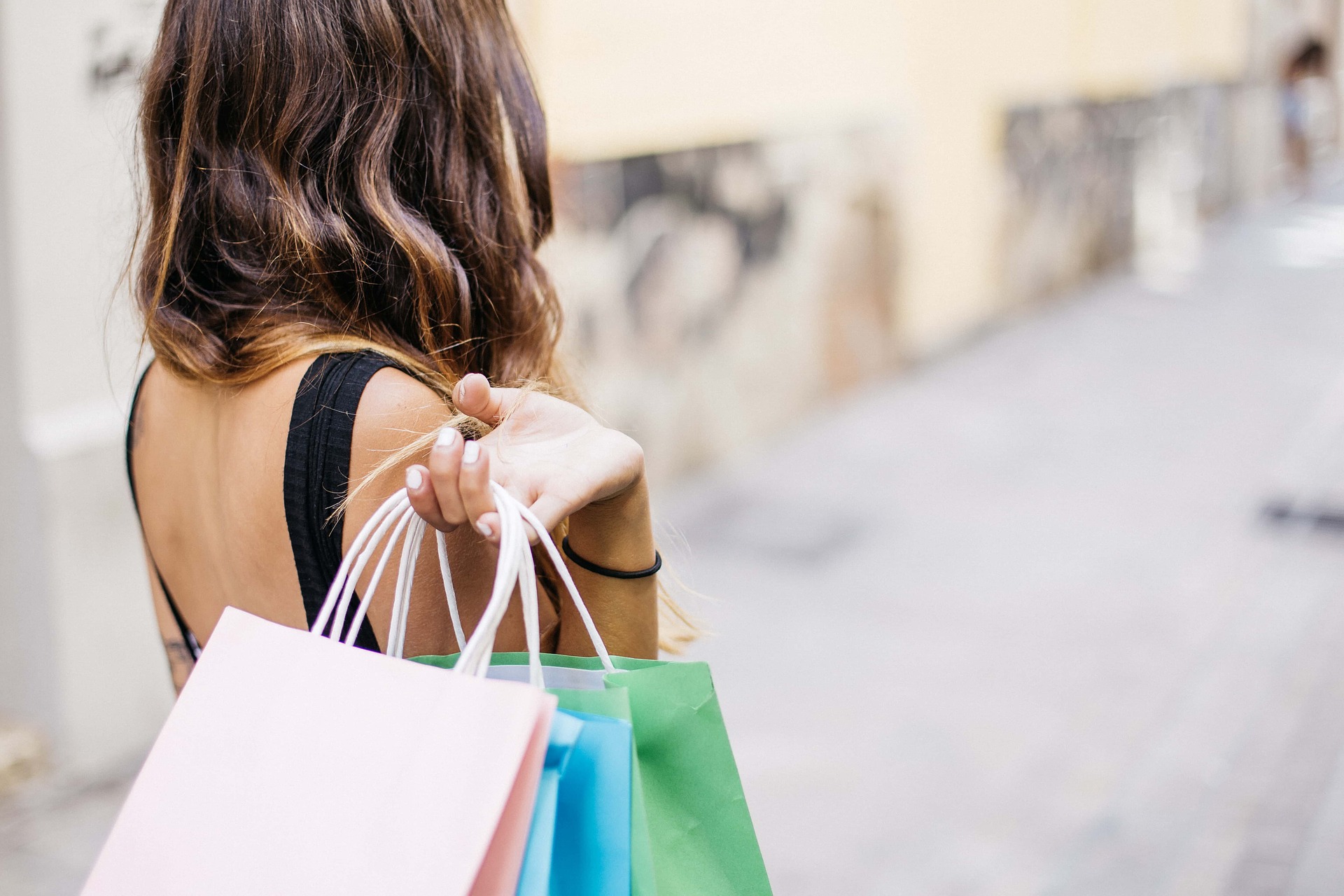 back of a woman holding shopping bags over her shoulder