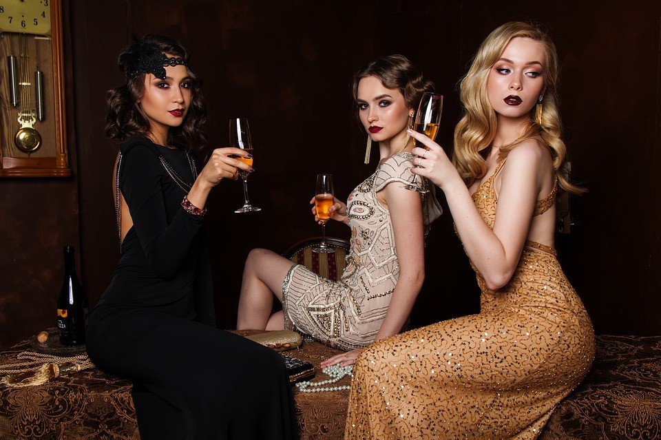3 women in a darkened room in party clothes with a 20's theme