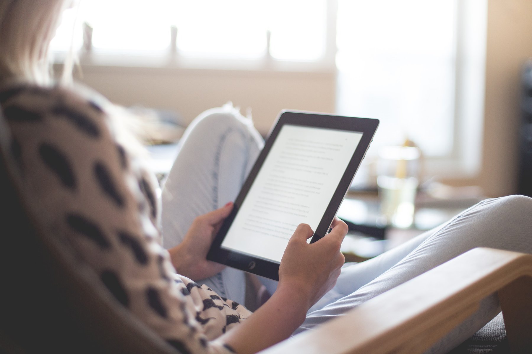woman on a bed looking at an e-reader