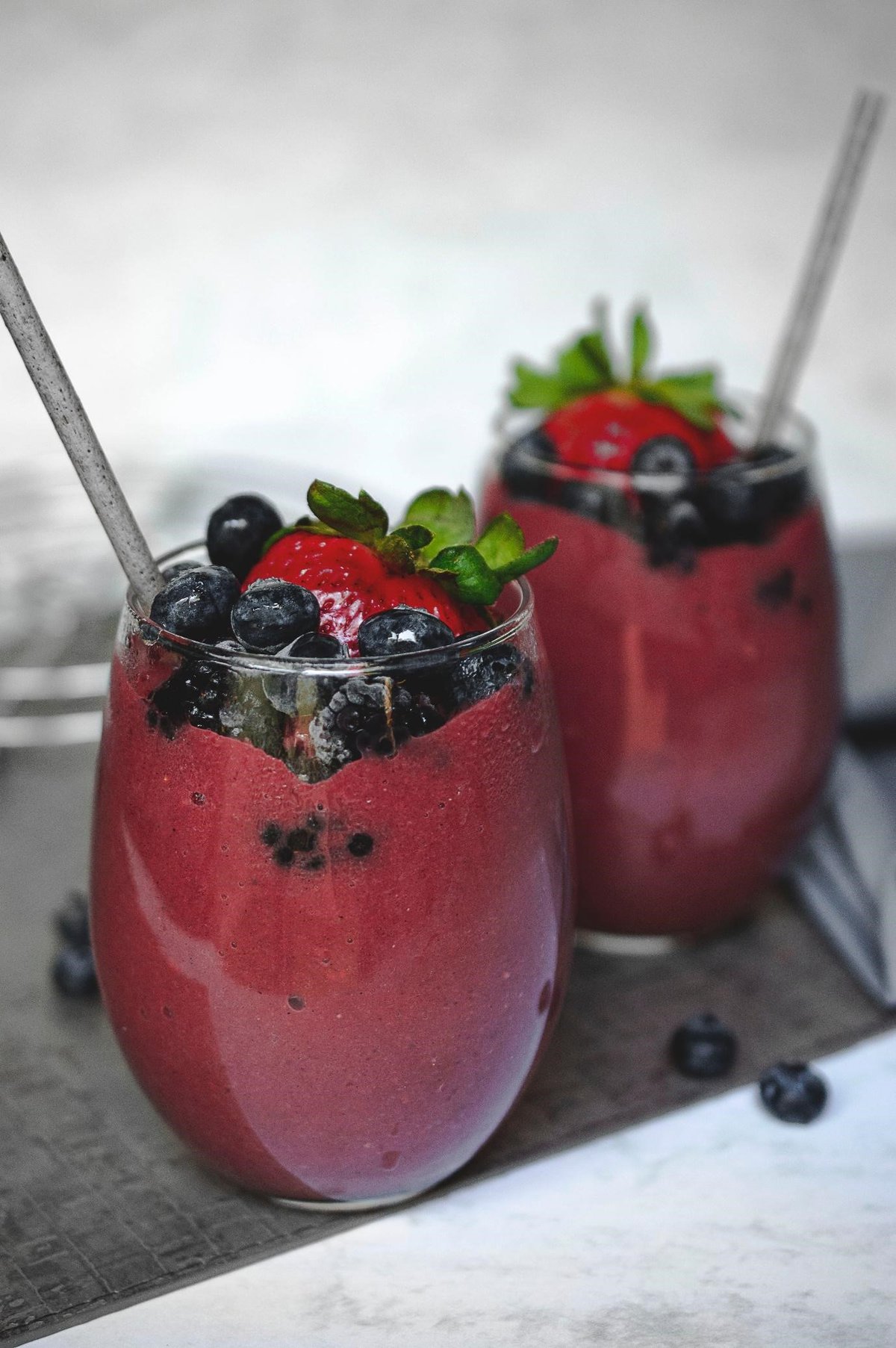 two glasses containing a berry smoothie