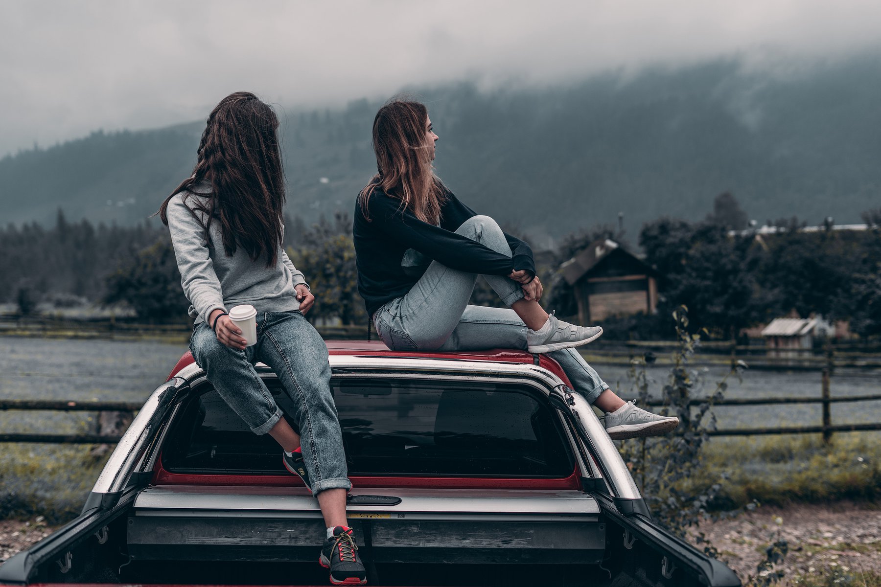 tow young girls sitting on a car
