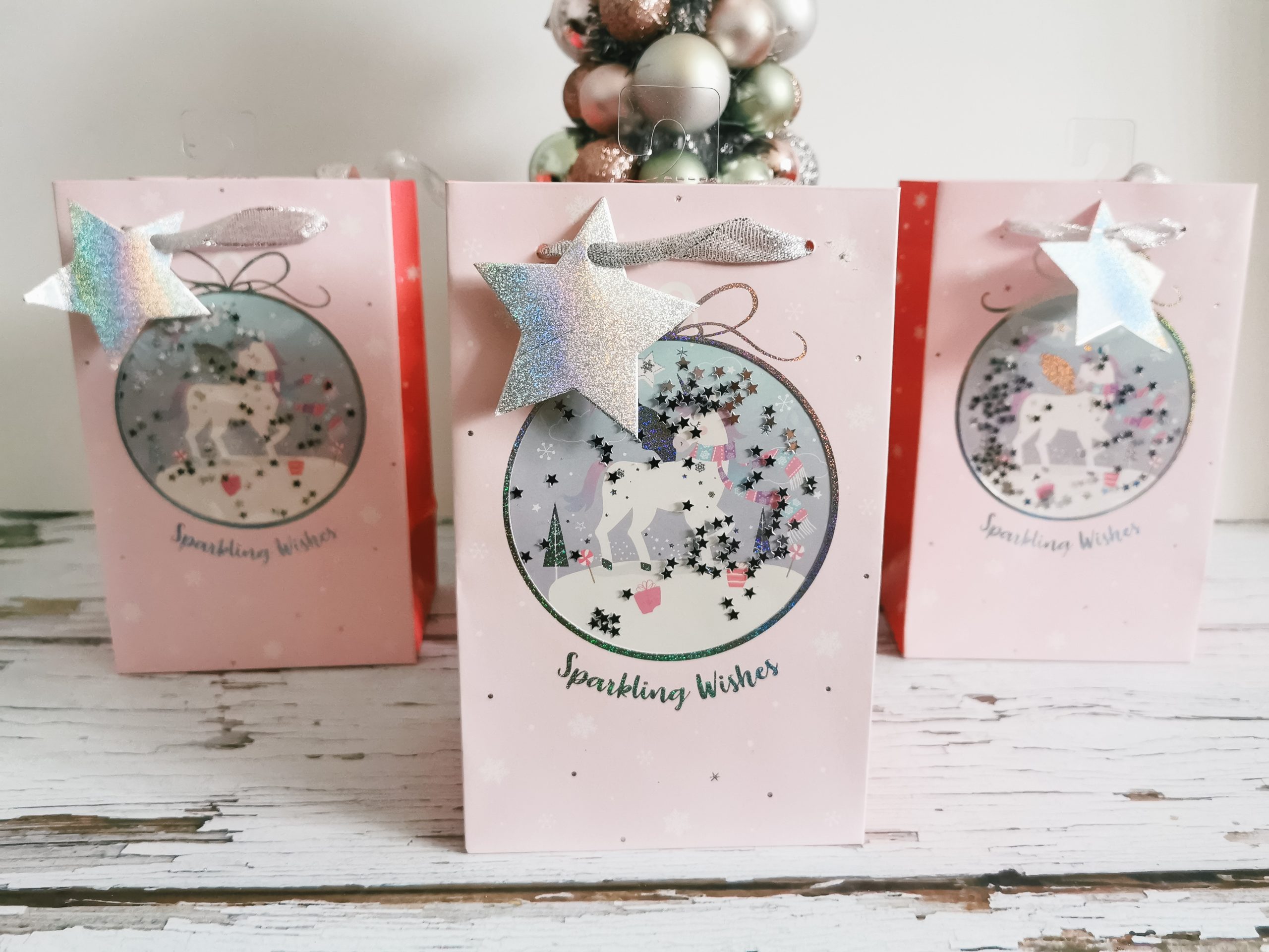 empty gifts bags in front of a pastel coloured bauble tree