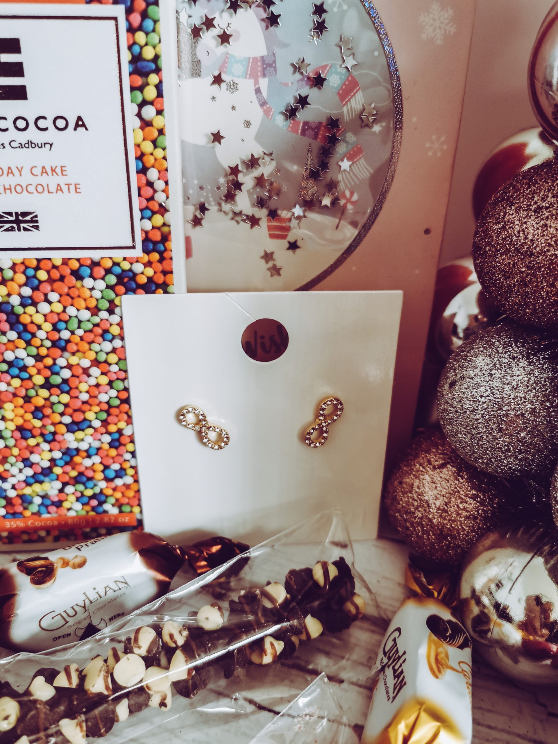 a pair of earrings surrounded by chocolates