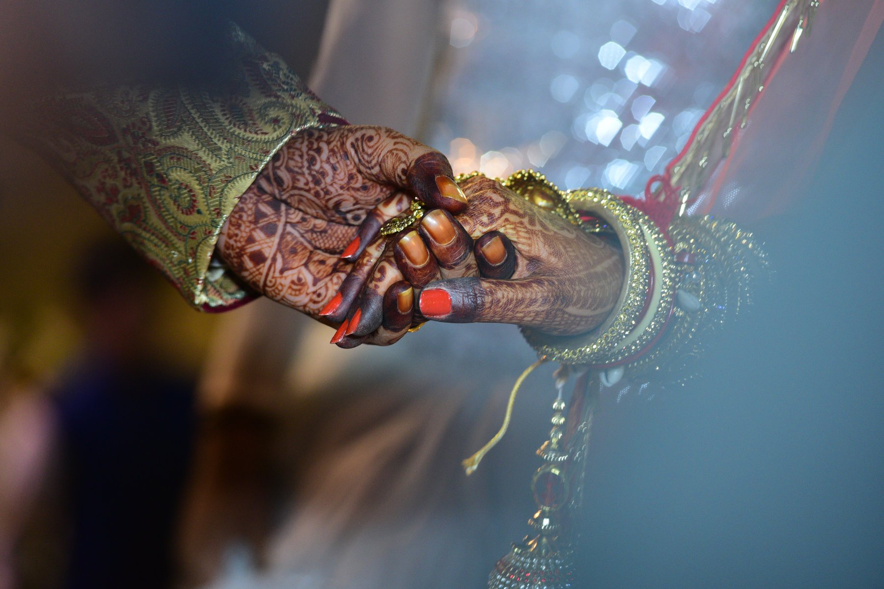 holding hands covered in henna tattoos and jewellery